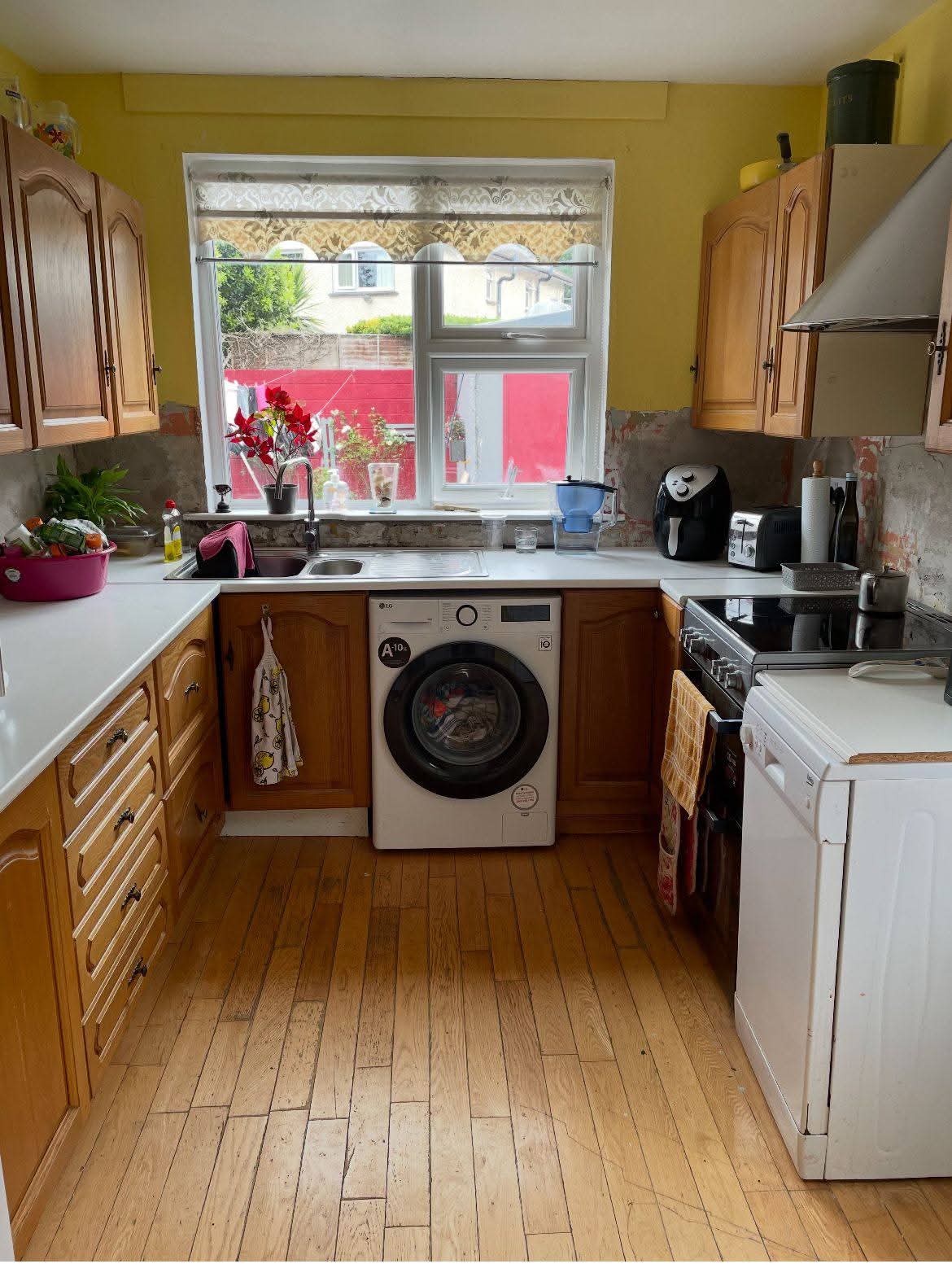 Before: dated pine kitchen units with worn white worktop, old washing machine and bare plaster walls