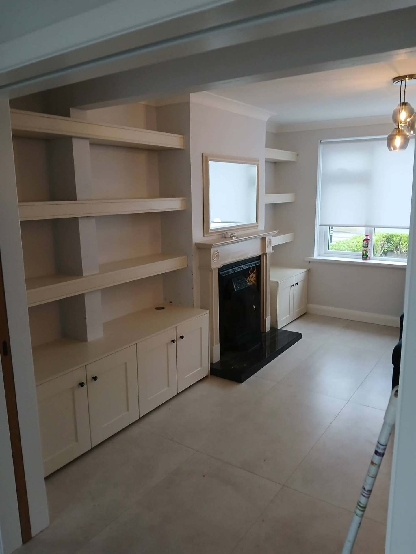 Cream alcove shelving and cupboards fitted either side of a period fireplace