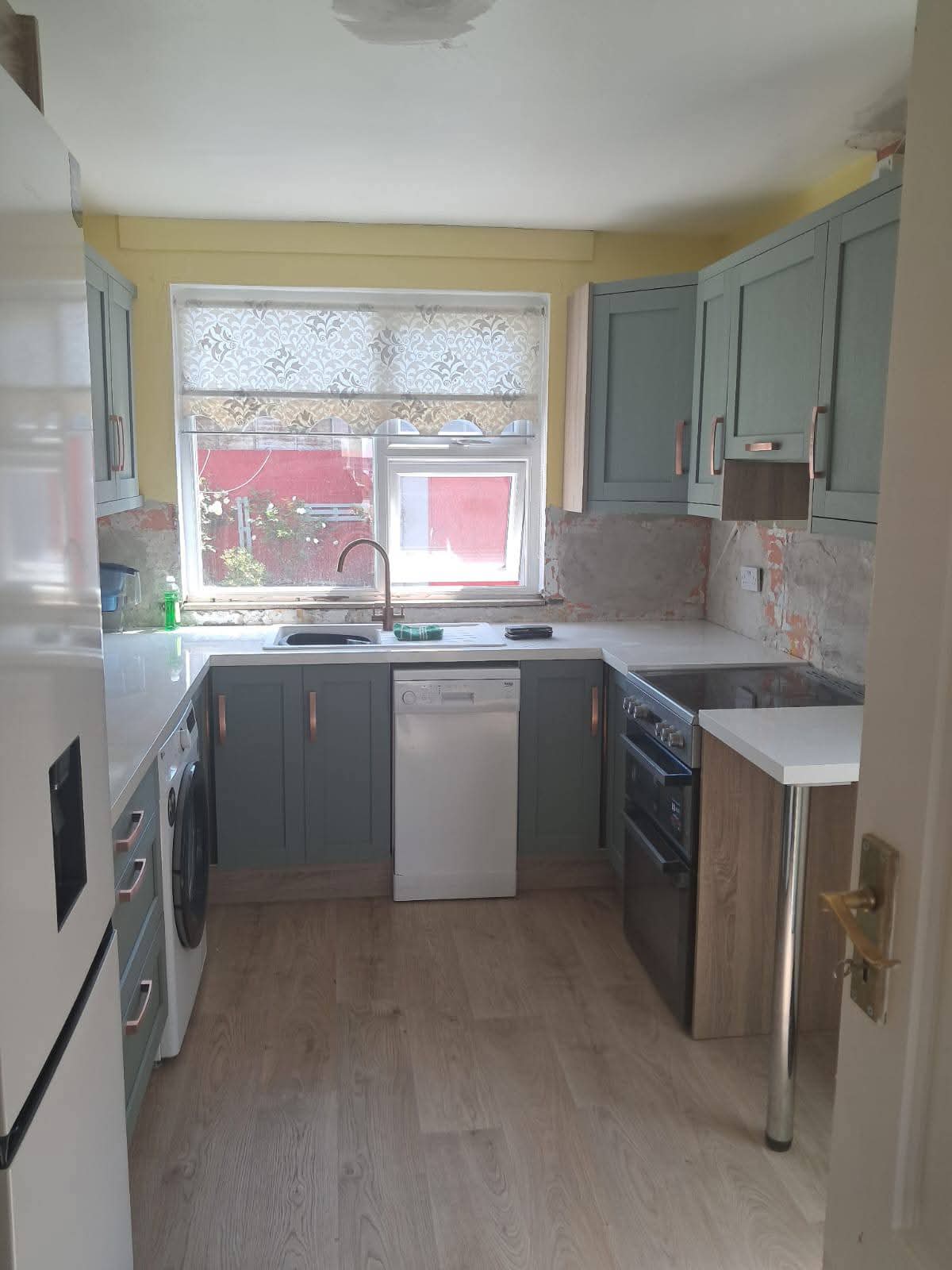After: fitted sage and graphite shaker kitchen with copper handles, white worktops, integrated oven and new oak-effect flooring